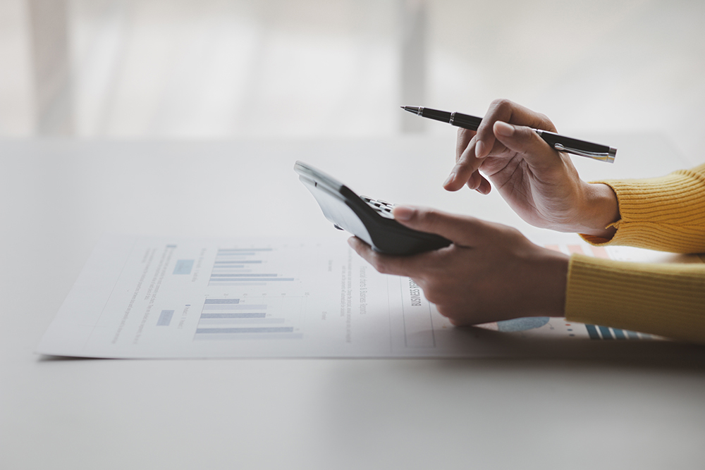 Businessman using a calculator to calculate numbers on a company's financial documents